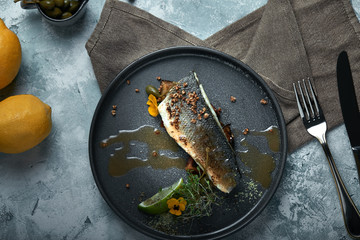 Grilled seabass with eggplant and lime. Horizontal top view, top shot. Copy space, gray concrete marble background, soft light. Food Fashion Photo.