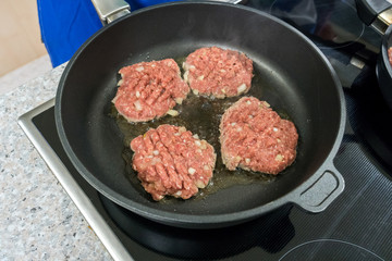 Burger patties are fried in a pan