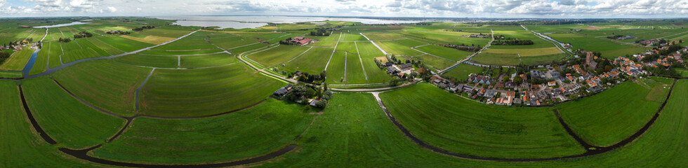 360 degrees aerial panorama of the agrarian green pasture fields with its irrigation infrastructure of ditches and trenches surrounding the small traditional village of Ransdorp near Amsterdam
