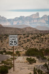 Speed limit 25 mph sign in the desert of West Texas with mountains in the background