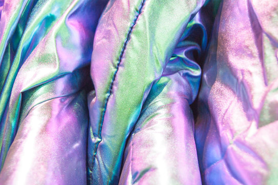 Details - beautiful shiny down jackets hang in a row in the store, forming a beautiful abstract shining texture. Style, fashion, element, glitter.