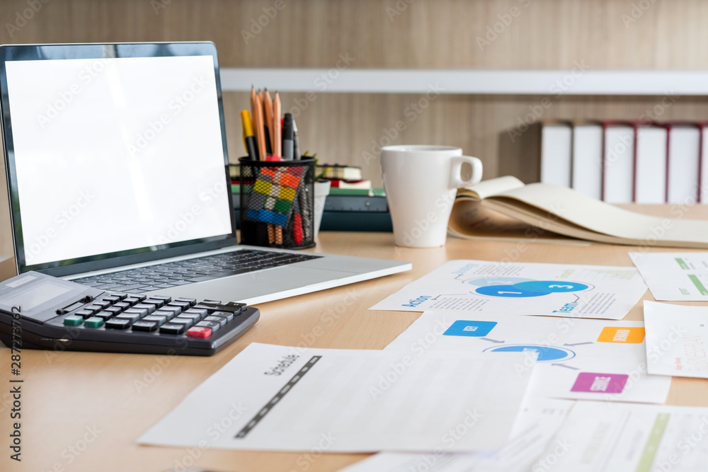 Poster mockup laptop computer screen with business chart market,caculator,coffee cup,pencil box on desk at 