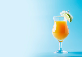 Orange summer alcoholic cocktail with mango juice, rum, liqueur, lime and ice, blue background, copy space