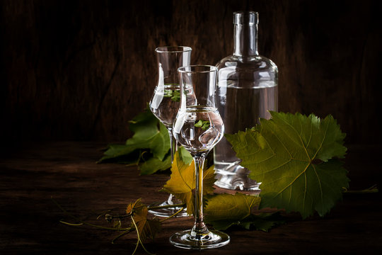 Grape vodka, pisco - traditional Peruvian strong alcoholic drink in elegant glasses on vintage wooden table, copy space