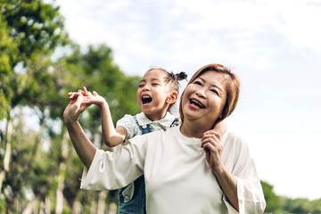 Fototapeta premium Portrait of happy grandmother and little cute girl enjoy relax together in summer park.Family and togetherness
