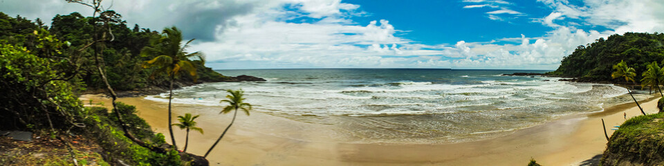 A panoramic view of Engenhoca beach in Itacaré, Bahia, showcasing turquoise waters, gentle waves, and preserved nature on a sunny day under a clear blue sky.