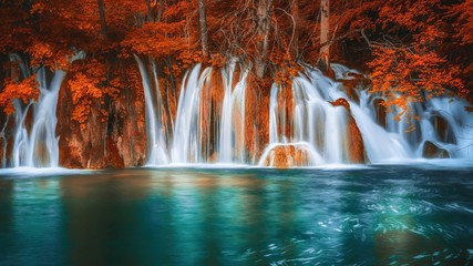 Waterfalls dropping into a natural pool, in a fantasy autumn red forest.