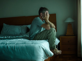 dramatic lifestyle portrait of man sitting depressed on bed crying desperate feeling sad suffering anxiety crisis and depression problem