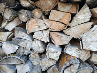 Heap of cut firewood. Sawn and cut tree trunks drying outdoors in the sun. Wood stacked and stored.