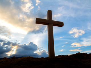 Silhouettes of crucifix symbol with bright sunbeam on the colorful sky background