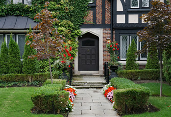 front door and garden of Tudor style house covered in vines