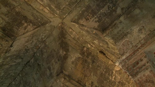 A hand held, low angle, panning, medium shot of the old walls destroyed by the irreversible passing of time.