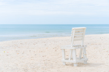 Vintage white wooden chair left on the beach.  The beautiful beach in Thailannd with beautiful blue sky and cloud background.
