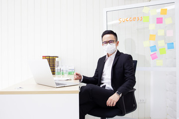 Portrait of Asian business man working in the office and masked a hygiene mask on his face.