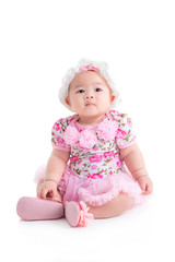 Full length of little asian baby girl in sweet pink dress sitting isolated over white background