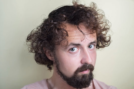 portrait of a young guy with long dirty hair on his head. Looks at the camera.