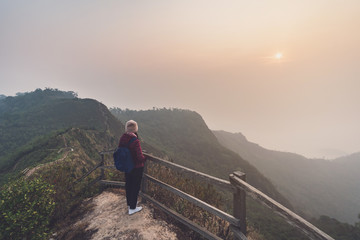 Young woman traveler looking at sunset over the mountain