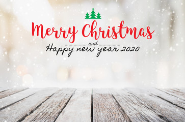 Christmas and Happy new year 2020 on empty wood table top on blur bokeh background with snowfall - can be used for display or montage your products.