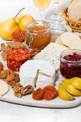 assortment of gourmet cheeses and snacks on board, vertical