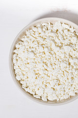 bowl of fresh farm cottage cheese on a white background, closeup top view