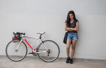 Girl with a bicycle Waiting beside the wall with impatience