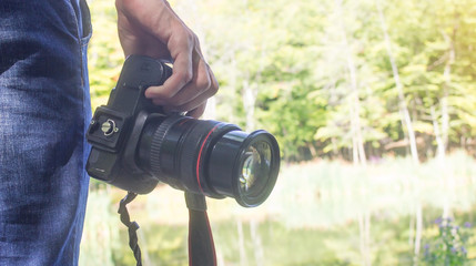 Professional photographer holding dslr camera in nature.