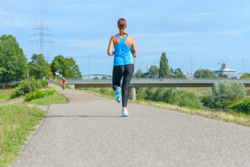 Fototapeta na wymiar Athletic woman jogging along a rural road