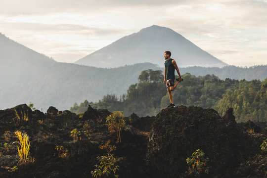 Man doing stretching and preparing for workout and running outdoors. Amazing mountain view on background. Adventure sports concept.