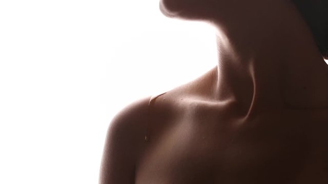 Girl on a white isolated background with clean skin. A drop of cosmetic oil flows down the body. Shoulders close up.