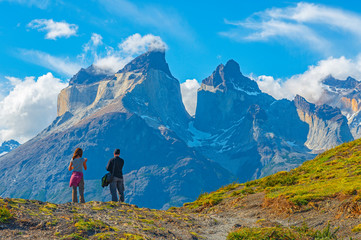 Twee toeristen, een man en een vrouw, kijken naar een gezichtspunt van de Andes-toppen van Cuernos del Paine, nationaal park Torres del Paine, Puerto Natales, Patagonië, Chili.