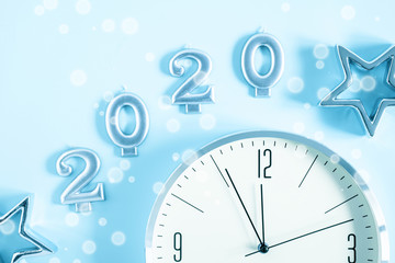 Happy New Year 2020. Christmas clock and star on pastel blue background. Flat lay, top view, copy space