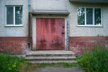 Red door to the utility room for storing equipment of janitors in a five-story city building