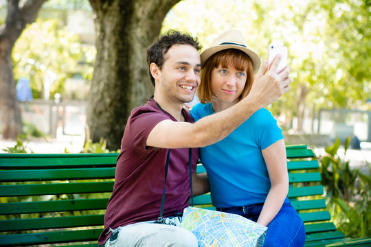 Young tourist couple taking selfie with mobile phone outdoors.