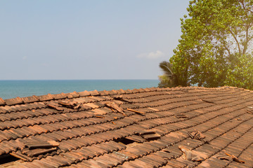 Broken old terracotta tile on a roof on sea background. Toned with sunlight. Summer time.