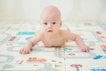 Newborn baby lying on his stomach on the playing Mat with city cars