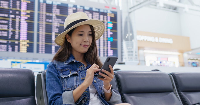 Woman use of cellphone to check the flight schedule at the airport