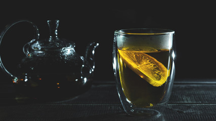 hot fresh black tea with lemons in transparent thermocup. Glass teapot. Tea ceremony