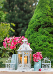 Floral table arrangement with pink roses and romantic lanterns. Garden party.