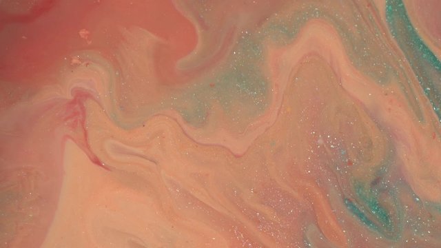 Close up of peach glitter texture background. Pastel coral, blue and pink colors liquid paint. Abstract fluid makeup composition. Hypnotic mixing and movement of the ink