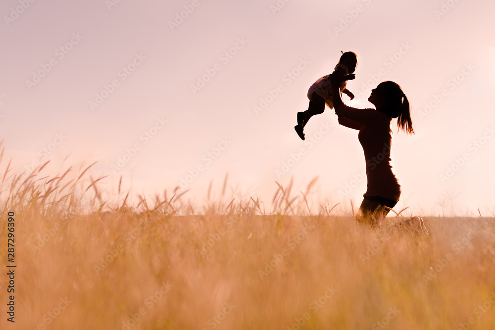 Wall mural mother playing with her baby outdoor, silhouette.