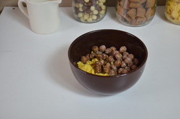 Breakfast cereal, chocolate balls in a brown bowl. Healthy breakfast. Diet Bowl and spoon with corn flakes isolated on white background