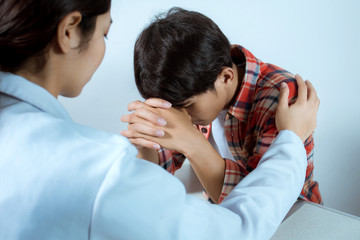 Female Doctors consoling patient use your hand to shoulder to help him relax. While sitting at your desk. The concept of counseling and health care.