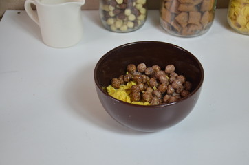 Breakfast cereal, chocolate balls in a brown bowl. Healthy breakfast. Diet Bowl and spoon with corn flakes isolated on white background