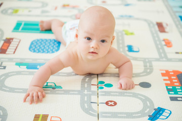 Newborn baby lying on his stomach on the playing Mat with city cars