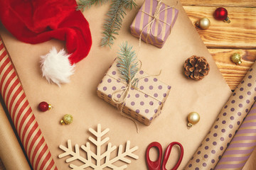 Christmas festive mood. Flat-lay of decorations, ribbons, gift paper, wrapped gift on wooden...