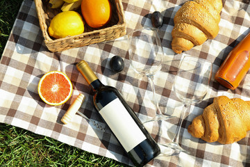 Composition with wine, croissants, fruits and towel on grass, top view