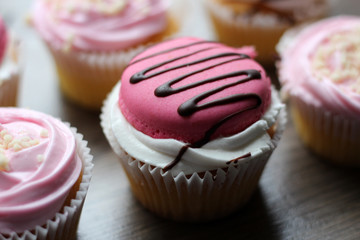 Pink cup cake on a wooden background, so close