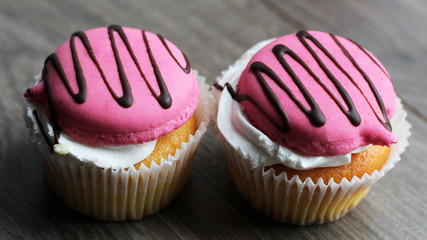Two pink cup cakes on a wooden background