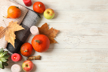 Pumpkins, clothes, leaves, candles and apples on wooden background, copy space
