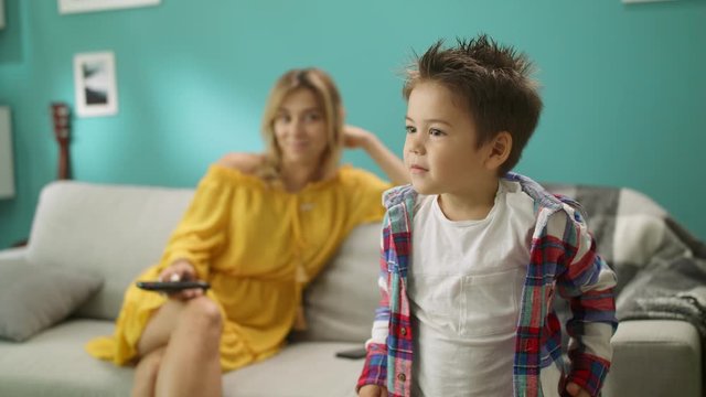 Portrait of boy who emotionally watches cartoons with his mother
